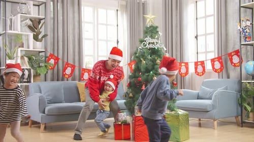 Kids run around the tree with dad.