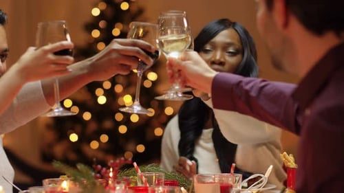 Glasses meet in front of the tree lights.