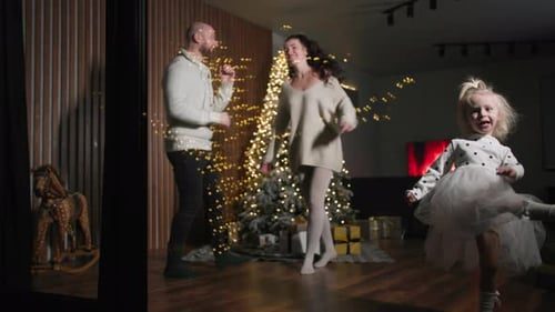 Mom, dad and their little girl dancing by the tree.