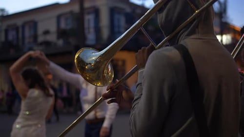Trombone in front, people dancing in the street behind.