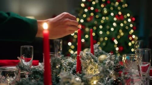 A hand lights the candles on the set table.