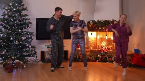 The family dancing in pajamas by the fire.