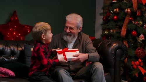 A boy gives grandpa a gift and a hug.