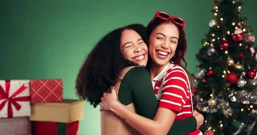 Two friends hug and laugh by the tree.