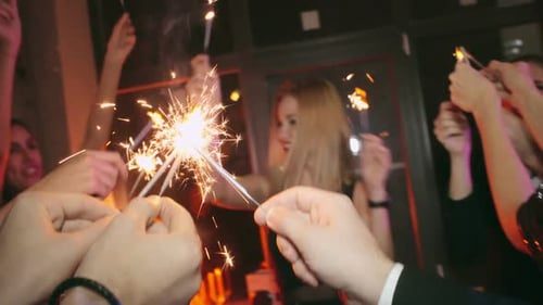 Friends wave sparklers at the party.