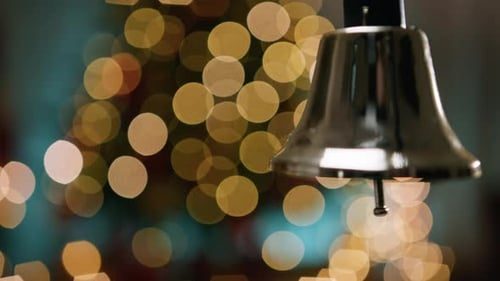 A silver bell, gold lights behind.