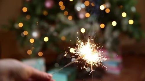 A sparkler in front of the tree.
